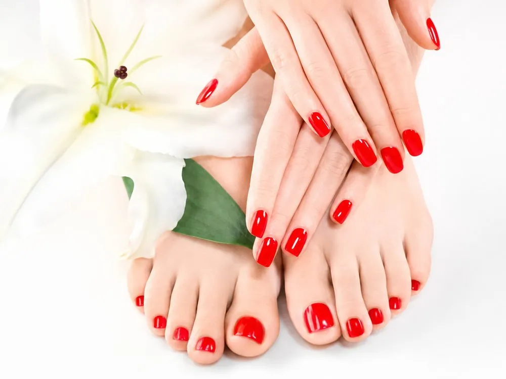 Mains aux ongles vernis de rouge, après une pose à l’institut Clama Jolie